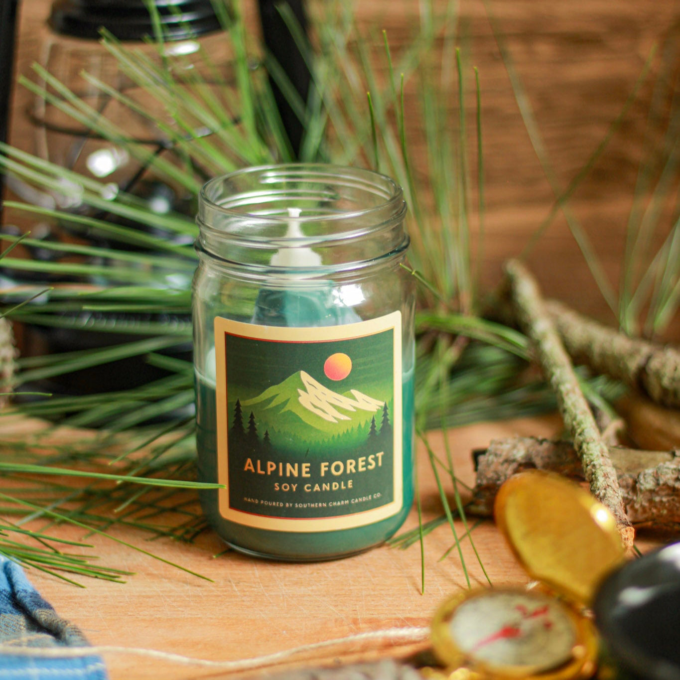 Candle labeled 'Alpine Forest' with camping-themed decor in the background