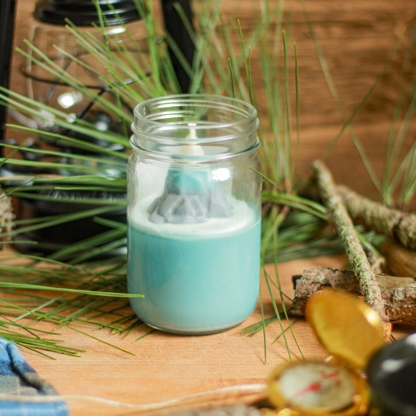 Jar with a small mountain model on a wooden surface with greenery and a lantern in the background